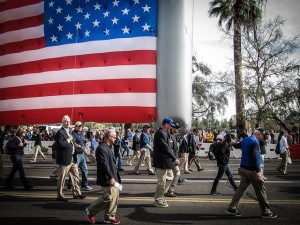 Mr. Bill Pupo (front w/red shoes) marches with the Blue Blazers during the Fiesta Bowl Parade carrying the U.S. Flag for Fighter Country Partnership